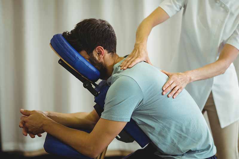 Physiotherapist giving back massage to a patient in the clinic